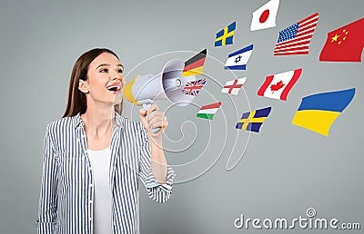 Portrait of interpreter with megaphone and flags of different countries on grey background Stock Photo