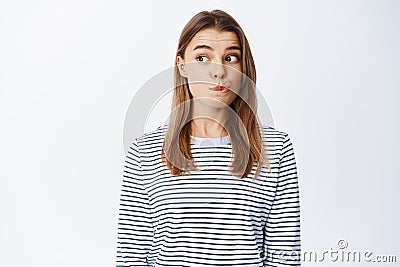 Portrait of intrigued blond girl checking out something interesting, pucker lips and looking left with tempted face Stock Photo