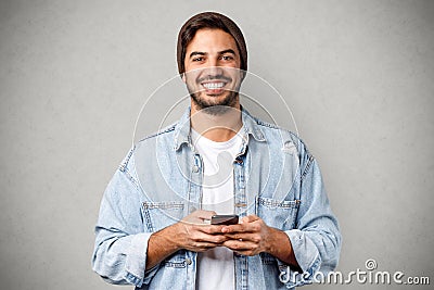 Portrait of joyful caucasian guy smiling holding smartphone Stock Photo