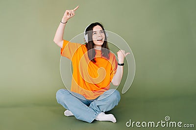 Portrait of a joyful woman wearing headphones, expressing enthusiasm and approval while pointing both thumbs towards Stock Photo