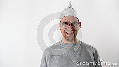 Portrait of joyfully smiles attractive man in foil hat and glasses. Emotional handsome guy with a tinfoil helmet to the brains Stock Photo