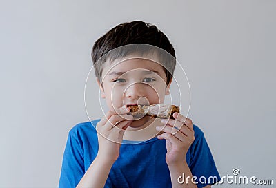 Portrait Kid with yummy face enjoy eating roasted chicken drumstick in the garden, Happy of cute boy eating grilled chicken, Stock Photo