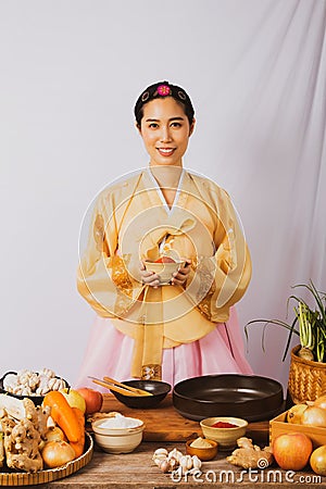 Portrait korean asian beautiful woman wearing golden hanbok, preparing food, folk wisdom Korean Recipes Kimchi Pickles, she is hap Stock Photo