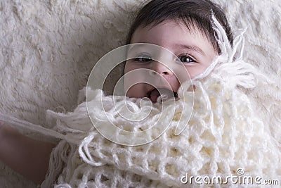 Portrait of laughing little baby girl under knitted cloth Stock Photo