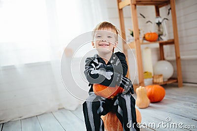 Portrait of laughing little boy in a skeleton costume is ready to celebrate Halloween. Boy in a halloween dress-up room. Stock Photo