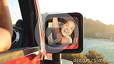 Portrait Of Laughing Woman Reflected In Car Wing Mirror Having Fun In Open Top Car On Road Trip Stock Photo