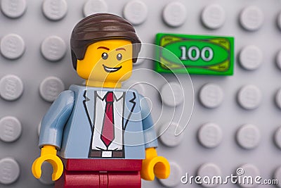 Portrait of a Lego businessman minifigure standing against Lego gray baseplate with Lego banknote on it Editorial Stock Photo