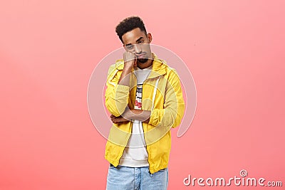 Studio shot of bored indifferent good-looking young dark skinned guy with beard and afro hairstyle leaning head on fist Stock Photo
