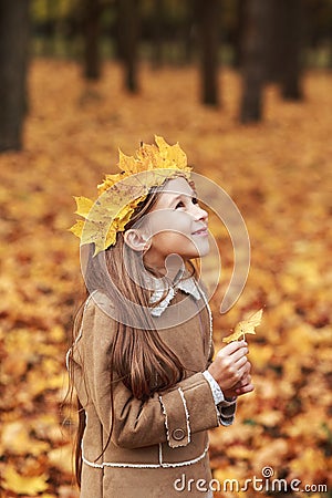 Portrait liitle cute girl with crown of leaves in autumn park Stock Photo