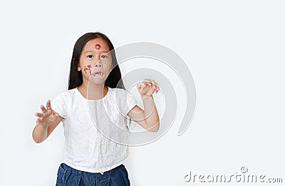 Portrait of little Asian child girl with face make up in Halloween costume looking at camera with frightening expression over Stock Photo