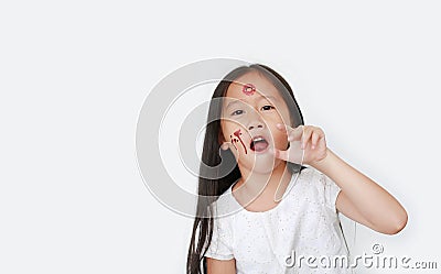 Portrait of little Asian child girl with face make up in Halloween costume looking at camera with frightening expression over Stock Photo