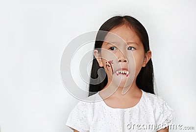 Portrait of little Asian child girl with face make up in Halloween costume looking out with frightening expression over white Stock Photo