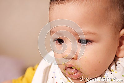 Portrait of little baby boy eating food. Baby with a spoon in feeding chair. Cute baby eating first meal Stock Photo