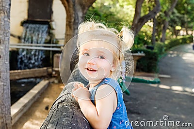 Close up Portrait of little blondy toddler Girl Smiling at Camera. Happy kid walking outdoors in the park or zoo. Family recreatio Stock Photo