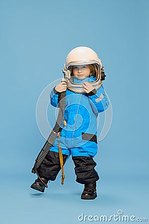 Portrait of little boy, child posing in astronaut costume over blue studio background. Fantastic game. Concept of Stock Photo
