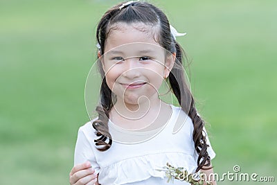 Portrait of little Caucasian girl with white t-shirt and hair tied up 2 sides is smiling looking at camera Stock Photo