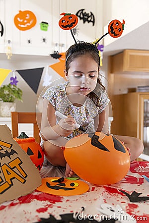 Little caucasian toddler girl painting a balloon to decorate her house during Halloween celebration Stock Photo