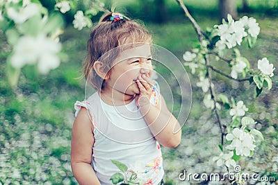 Portrait of little cute disheveled girl laughing and having fun outdoors among flowering trees in a sunny summer day Stock Photo