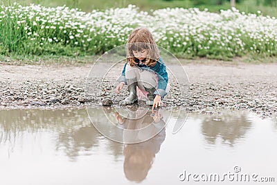 Portrait of little cute girl on the field with daisies and water Stock Photo