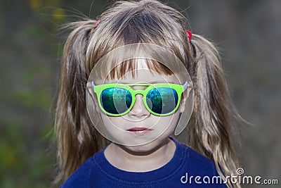 Portrait of little fashionable girl in green sunglasses outdoors Stock Photo