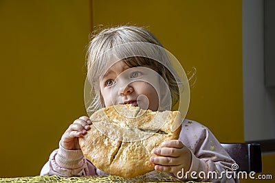 Portrait of a little girl eating a large pizza indoors on a neutral background. Concept: a snack while traveling, exotic local dis Stock Photo