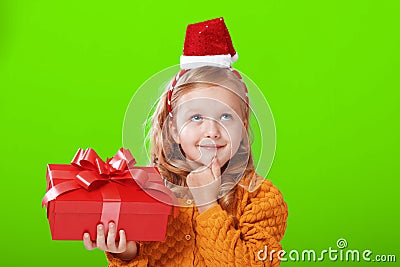 Portrait of a little girl in a sweater and a santa claus hat on a green isolated background. Stock Photo