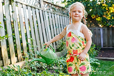 Little girl watering green plants on backyard Stock Photo