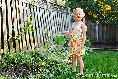 Little girl watering green plants on backyard Stock Photo