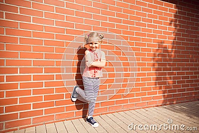 Portrait of little kid girl laughing at bricks wall background Stock Photo