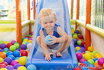 Portrait of little kid playing ball pit and enjoying time in kids entertainment and play area. Happy kid plays in kindergarten Stock Photo