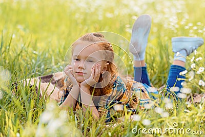 portrait of little pensive child resting on green grass Stock Photo