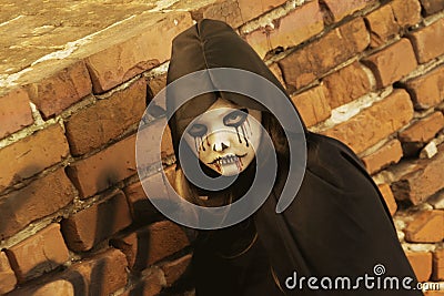 Portrait of a little teenager girl in a zombie costum against a brick wall. Halloween and day of the dead concept. Zombie looks at Stock Photo