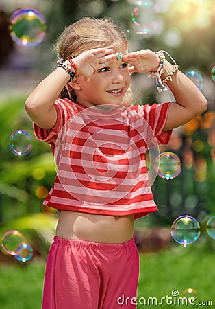 Portrait of little toddler hippie laughing girl covering her face with palms from the sun Stock Photo