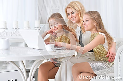 Portrait of little twin girls with mother using laptop at home Stock Photo