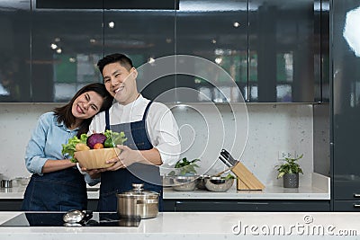 Portrait of a lovely couple in an apron holding a vegetable basket to cooking food Stock Photo