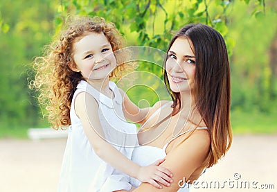 Portrait lovely young mother and cute daughter in sunny summer Stock Photo