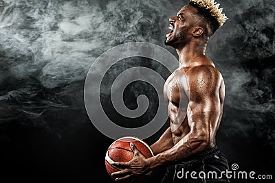 Portrait of afro-american sportsman, basketball player with a ball over black background. Fit young man in sportswear Stock Photo