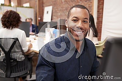 Portrait Of Male Customer Services Agent Working At Desk In Call Center Stock Photo