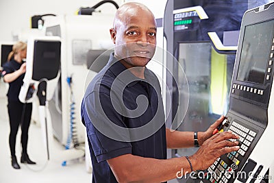 Portrait Of Male Engineer Operating CNC Machinery In Factory Stock Photo