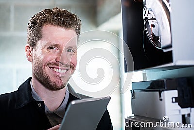 Portrait Of Male Heating Engineer Working On Central Heating Boiler Using Digital Tablet Stock Photo