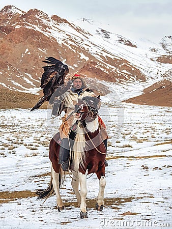 Portrait of a male hunter on horseback with a hunting golden eagle. Eagle hunters are individuals who train and hunt with golden Editorial Stock Photo