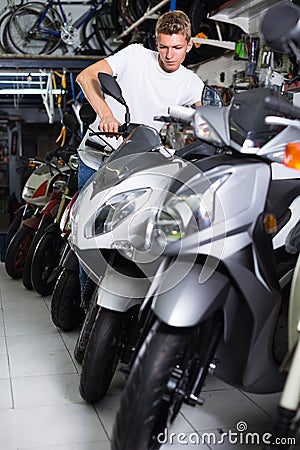 Portrait of male motorcyclist looking on the bike in the store Stock Photo