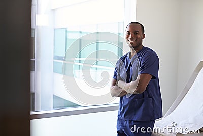 Portrait Of Male Nurse Wearing Scrubs In Exam Room Stock Photo