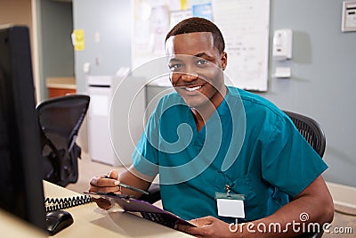Portrait Of Male Nurse Working At Nurses Station Stock Photo