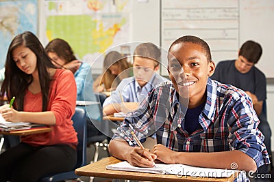 Portrait Of Male Pupil Studying At Desk In Classroom Stock Photo