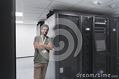 Portrait of male technician or network administrator standing brave as a hero with arms crossed in data center server Stock Photo