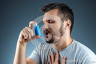 Portrait of a man with an asthma inhaler in his hands, an asthmatic attack. The concept of treatment of bronchial asthma, cough, Stock Photo