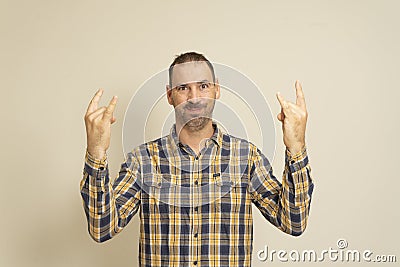 Portrait of a man on a beige background, shows a gesture with his hands Rock n Roll. The concept of body language. Stock Photo