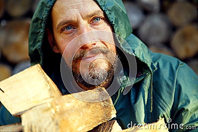 Portrait of a man with a bunch of chopped firewood. Bearded lumberjack with firewood for the fireplace. Stock Photo