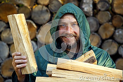 Portrait of a man with a bunch of chopped firewood. Bearded lumberjack with firewood for the fireplace. Stock Photo